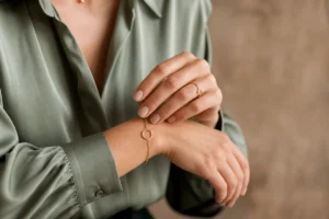 Personne élégante ajustant un bracelet doré pour un shooting photo professionnel dans un studio moderne et épuré.